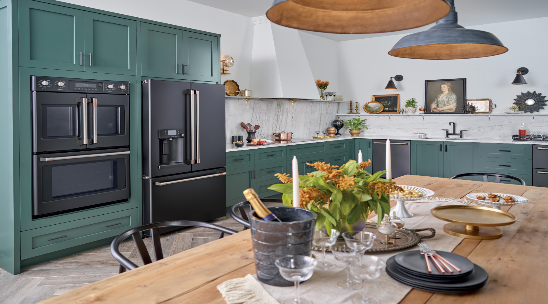 Kitched with green cabinents, black appliances and a natural wood table