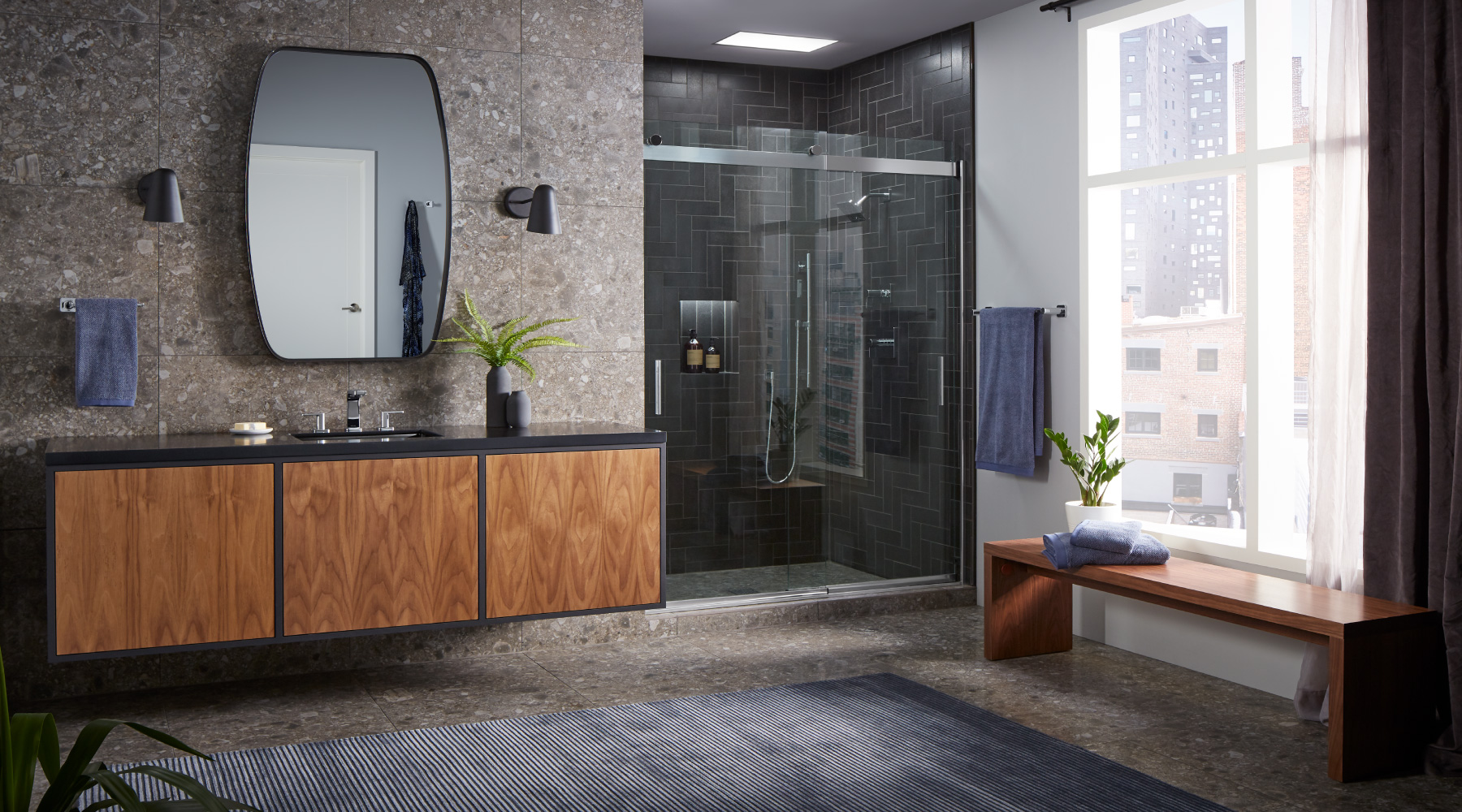 Modern city bathroom with stone walls, wood cabinents and a glass shower