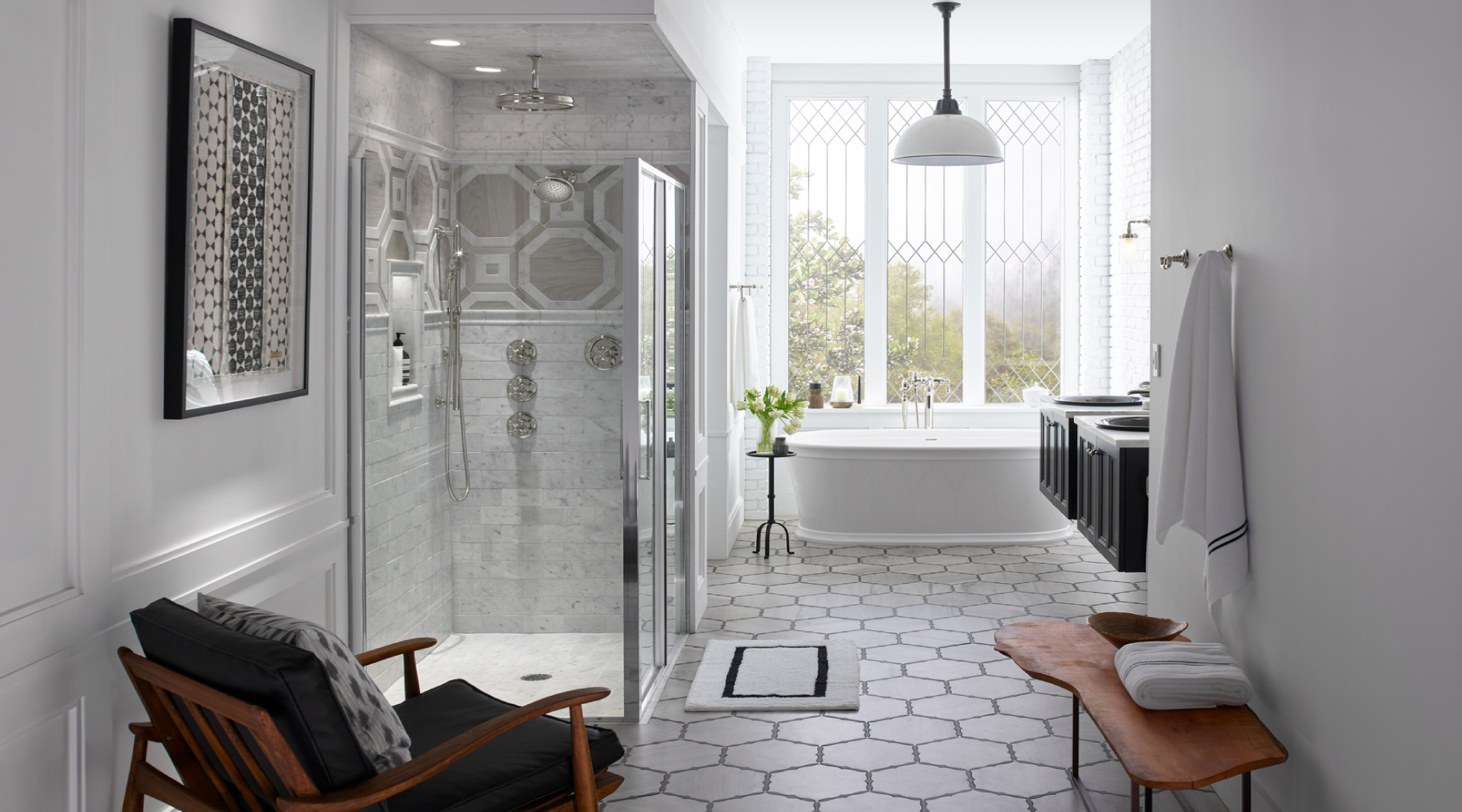 Bright bathroom with white walls and light grey tiles, glass shower and white tub in window